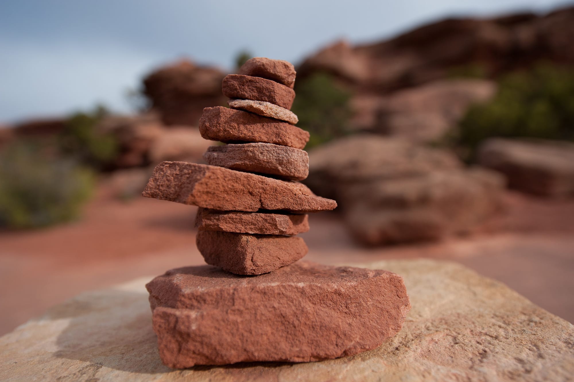 A balanced rock cairn on a sandstone ledge, marking the rugged trail through the desert landscape.