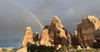 A rainbow arcs over towering sandstone formations in Canyonlands National Park, showcasing the rugged desert landscape.