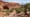 The large alcove along Alcove Spring Trail in Canyonlands, framed by red rock cliffs, rugged terrain, and desert vegetation.